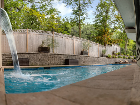 After photo of an inground pool renovation with paver patio and mature tree canopy