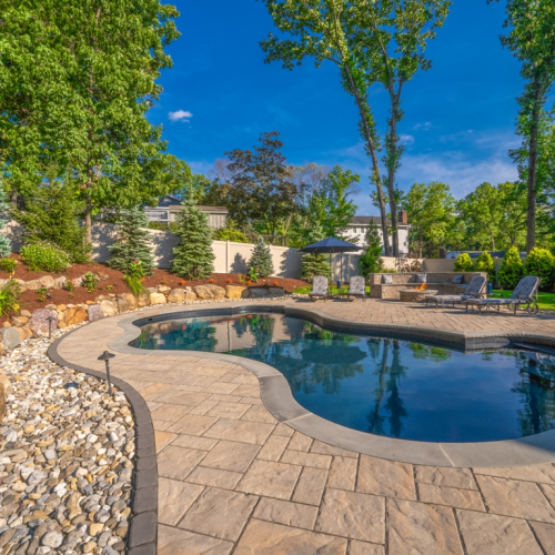 Elegant gunite pool surrounded by lush landscaping, vibrant flowers, and stone features, showcasing a tranquil outdoor space designed by EverClear Pools & Spas.