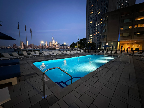 Evening poolside view with city lights visible across the Hudson River waterfront