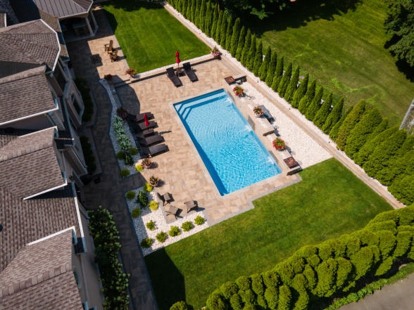Overhead aerial of the complete property layout with pool, paver patio, outdoor seating areas, and manicured landscaping