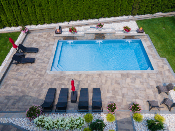 Elevated angle of the rectangular pool with fire bowl pillars, stone water feature, and red accent furniture