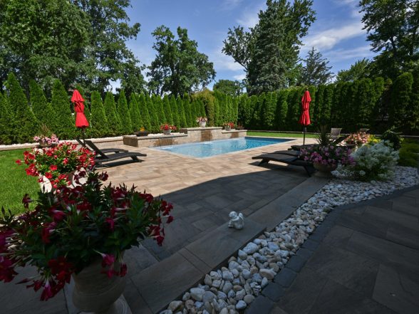 Landscape detail of flowering rose bushes and perennial plantings beside the pool paver patio