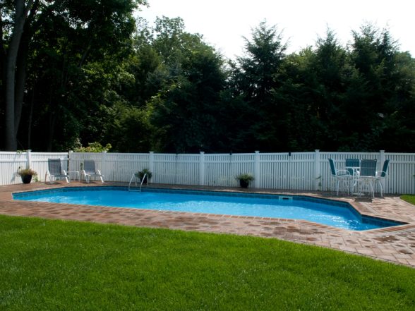 Alternate view of the freeform pool shape with brick paver patio and manicured lawn in Haskell, NJ