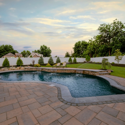 Gunite inground pool with stone coping and landscaped yard in Fairfield, NJ, showcasing EverClear Pools & Spas pool construction expertise.