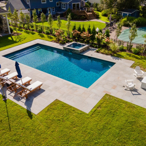 Modern backyard swimming pool with lounge chairs and umbrellas, landscaped garden, and spa area, showcasing EverClear Pools & Spas pool construction expertise.