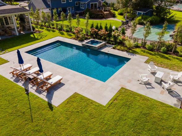 Modern backyard swimming pool with lounge chairs and umbrellas, landscaped garden, and spa area, showcasing EverClear Pools & Spas pool construction expertise.